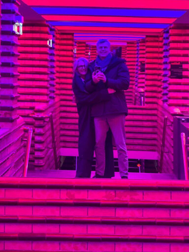 Zwei Besucher unter einer pink-violett beleuchteten Installation Wien