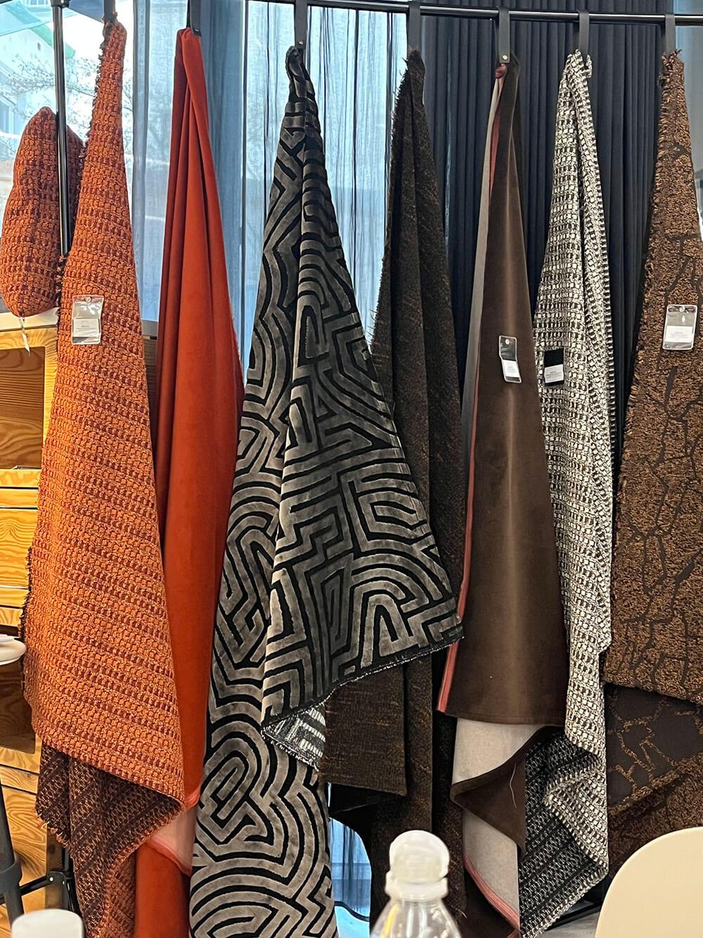 Große Stoffbahnen mit unterschiedlichen Mustern hängen auf einem Präsentationsständer